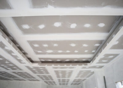 Maison neuve en cours de construction avec pose de cloisons en placo et isolation thermique. Installation de plaques de plâtre sur ossature métallique pour un projet résidentiel.