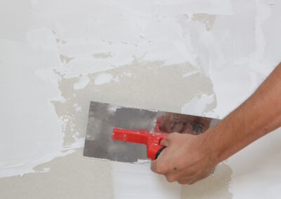 Maison neuve en cours de construction avec pose de cloisons en placo et isolation thermique. Installation de plaques de plâtre sur ossature métallique pour un projet résidentiel.