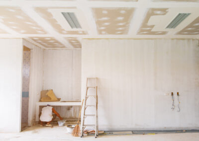 Maison neuve en cours de construction avec pose de cloisons en placo et isolation thermique. Installation de plaques de plâtre sur ossature métallique pour un projet résidentiel.
