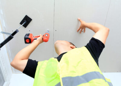 Maison neuve en cours de construction avec pose de cloisons en placo et isolation thermique. Installation de plaques de plâtre sur ossature métallique pour un projet résidentiel.